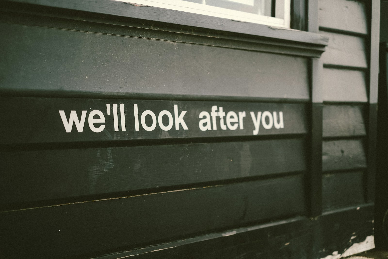 a sign on the side of a building that says we'll look after you