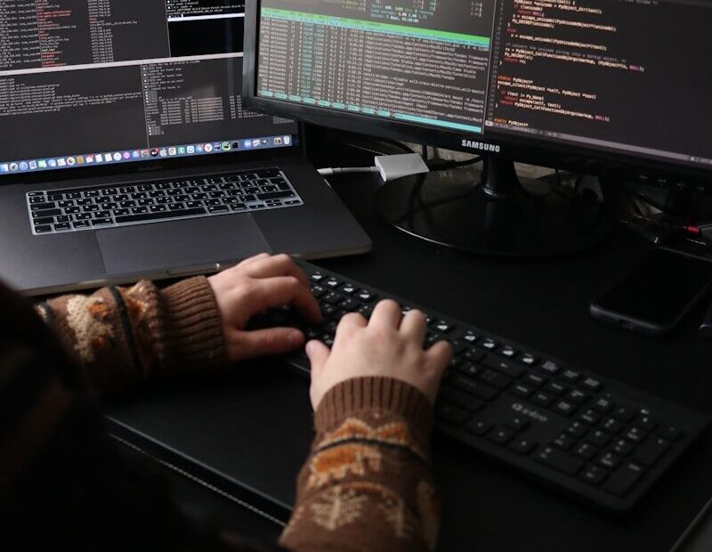 a person sitting at a desk with a laptop and a computer monitor